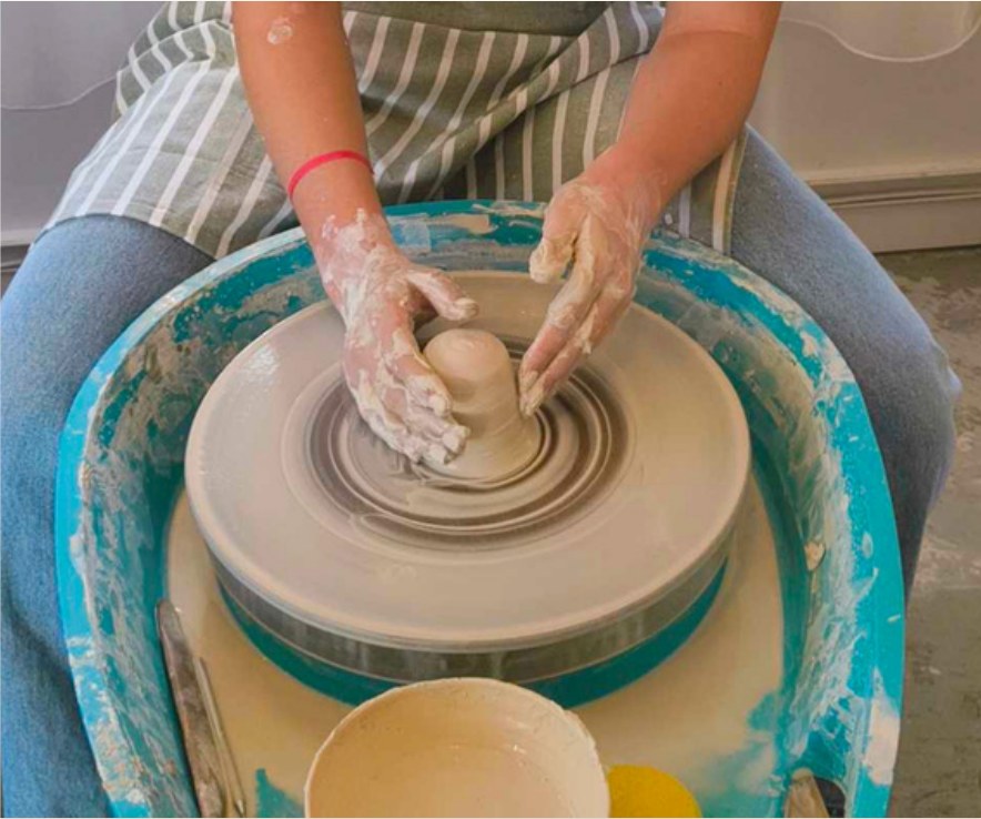 Student centring clay during a wheel throwing class