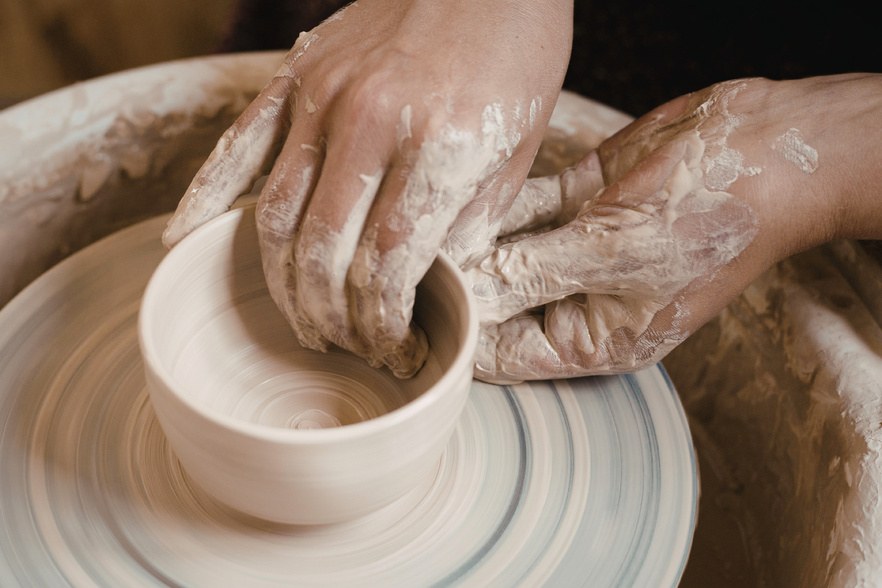 Hands centring clay on a pottery wheel