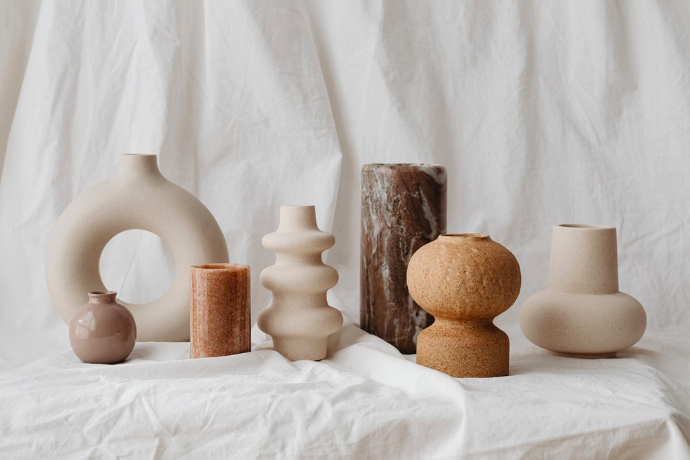 A row of pale hand-thrown vessels on linen