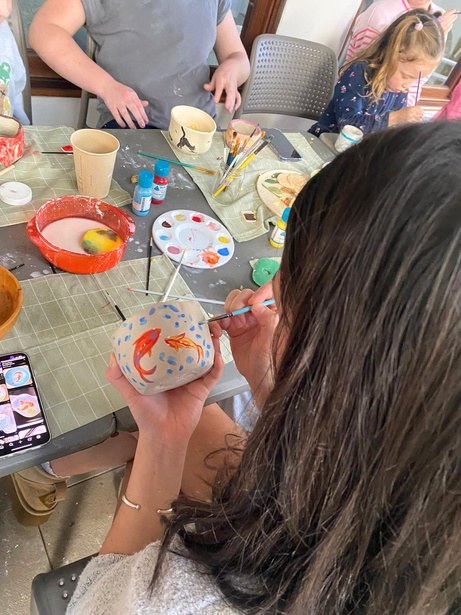 Student painting a hand-built piece with underglaze